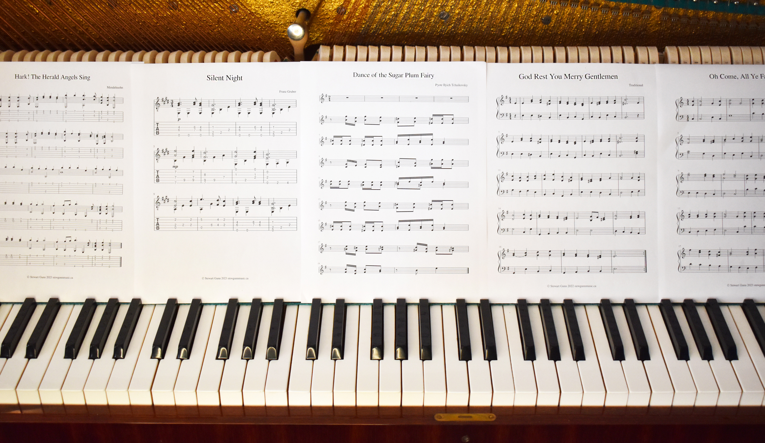 An image showing pages of sheet music spread out across the keys of a piano